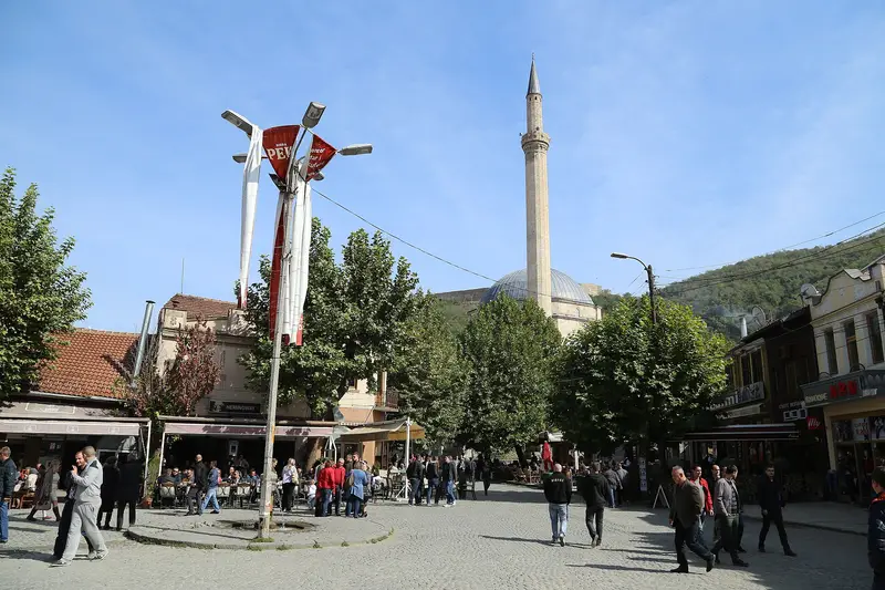 People crossing Shadërvan square in Prizren below the Sinan Pasha Mosque minaret