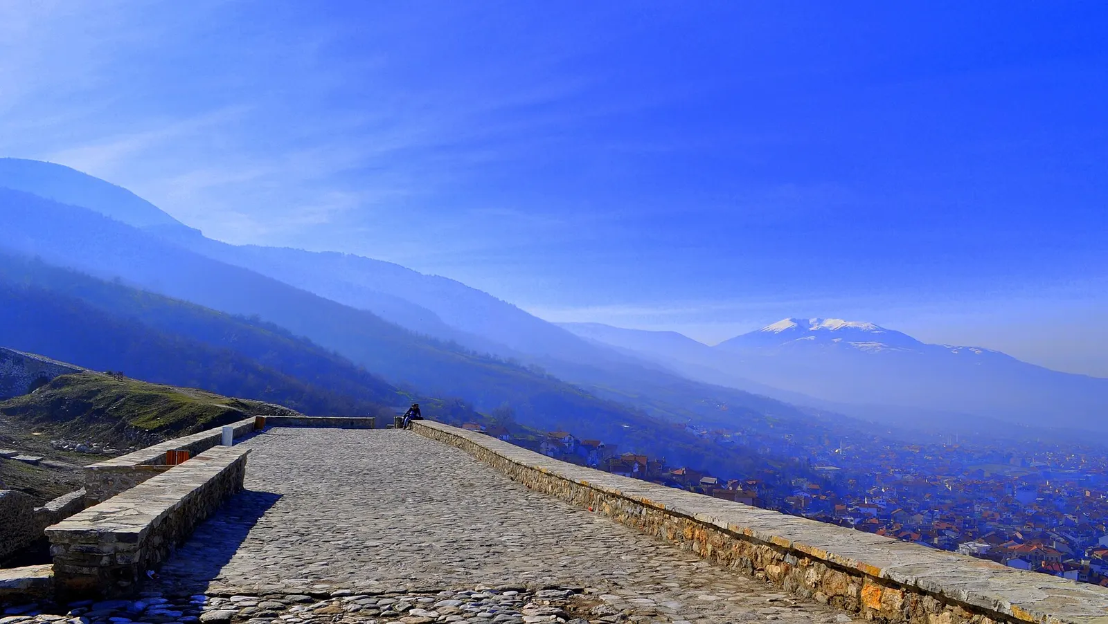 Stone path on top of Prizren Fortress with hazy blue mountains beyond